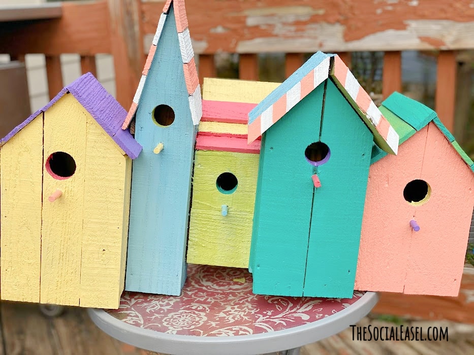 Birdhouses painted all colors outside on the porch table Outdoor Craft paint DIY Birdhouses The Social Easel Online Paint Studio