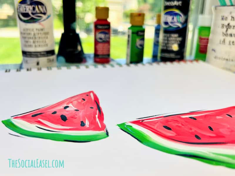 acrylic painted watermelon slices on a desk with paint bottles