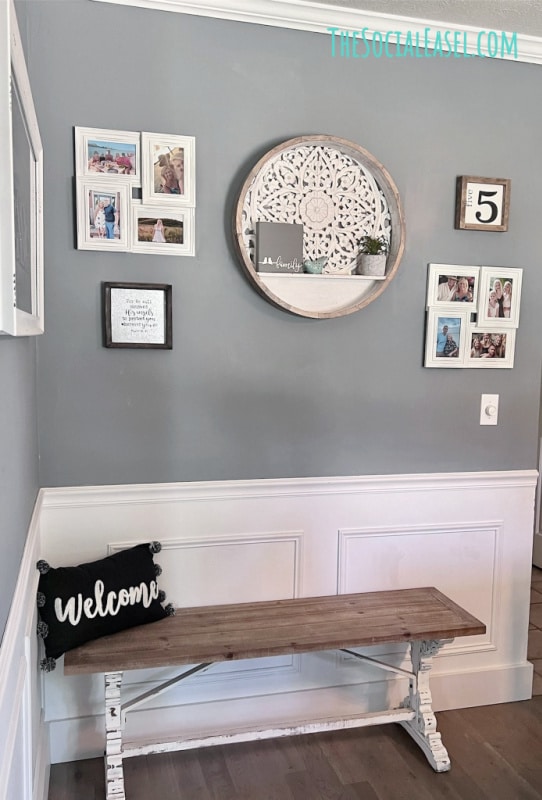 Gallery wall of decor and pictures hung on gray wall with bench