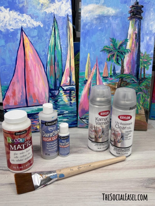 Bottles of sealer options for sealing an acrylic paintings lined up in front of a painting_how to seal an acrylic painting