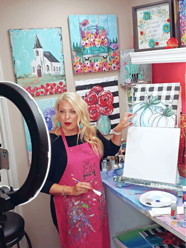 Christie Hawkins teaching how to paint a blue pumpkin in front of a ring light