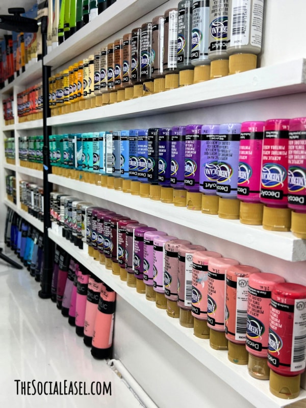 Paint lined up on a white wall shelf