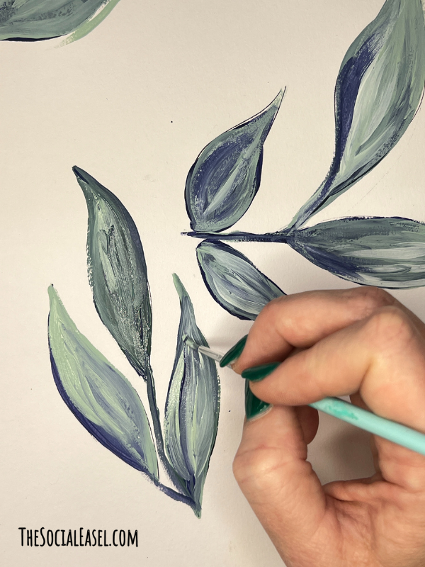 Christie pressing a small paint brush layering a lighter shade to the leaf.