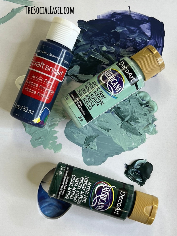Dark Blue, lighter and darker shade of green paint bottles on their side with samples of the paint colors.