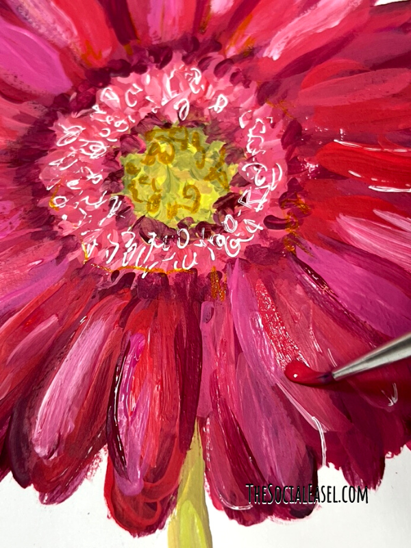 An acrylic painted Gerbera daisy with a paint brush making a brush stroke over the petal. 