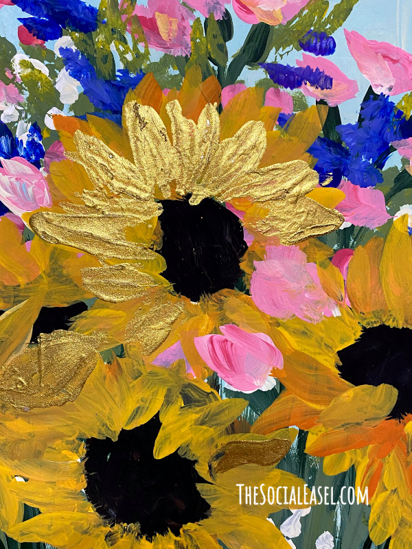 Sunflowers painted in gold with a metalic gold layer. Dark centers. Pink, blue,and white filler flowers. Greens inbetween the flowers. 