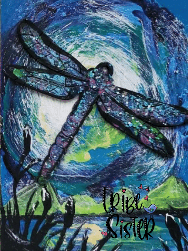 A dragon fly on a post card painted by a Tribe Sister