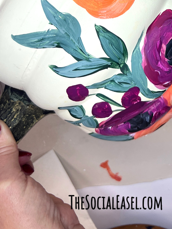 Green leaves and purple berries were added to the painted pumpkin. 