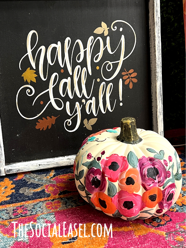 Happy Fall Y'all sign with a floral painted white pumpkin next to it.