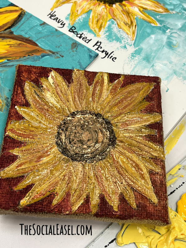 A Pallet knife painted sunflower with a rust colored background, brown center, and golden sunflower pedals.